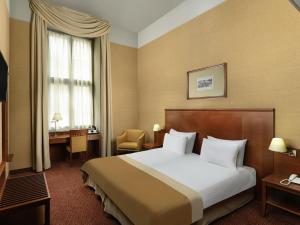 a hotel room with a bed and a desk and a window at Mercure Szekesfehervar Magyar Kiraly in Székesfehérvár +153 photos