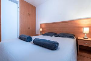 a bedroom with a bed with two blue pillows on it at L'Escapade Corse - À 80 mètres de la plage in San-Nicolao