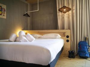 a bed with white pillows and a blue backpack at greet hotel Cernay Mulhouse in Cernay