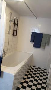 a bathroom with a white tub and a checkered floor at Eulen- & Altstadtnest in Peine +23 photos