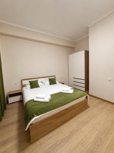a bedroom with a large bed with green sheets at N4 Alvina Complex in Tsaghkadzor