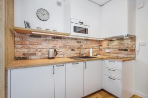 a kitchen with white cabinets and a brick wall at BOOKS & SUN by the Sea Air-conditioned Apartment in Władysławowo +15 photos