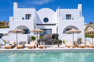 a villa with a swimming pool with chairs and umbrellas at Leon Luxury Suites in Imerovigli