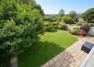 a garden with green grass and bushes at Sea Gem - large holiday cottage in Tenby with private parking in Tenby