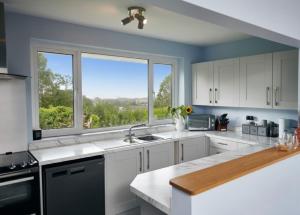 a kitchen with white cabinets and a large window at Sea Gem - large holiday cottage in Tenby with private parking in Tenby