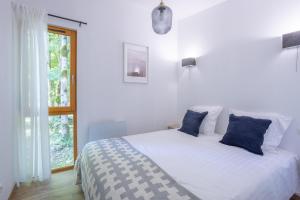 a white bedroom with a bed with blue pillows at Les Charmes C10 - Le Val Joly in Eppe-Sauvage