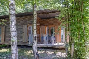a log cabin with a porch in the woods at Les Charmes C10 - Le Val Joly in Eppe-Sauvage
