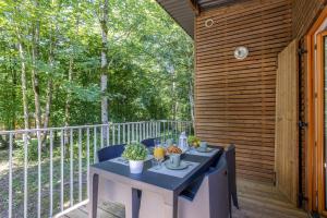 a table and chairs on a deck with trees at Les Charmes C10 - Le Val Joly in Eppe-Sauvage