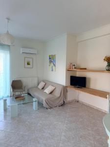 a living room with a couch and a tv in it at Green House Schinias in Káto Soúlion