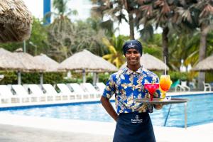 a man holding a tray with two cocktails on it at Coveñas - Condominio Puntepiedra Hotel in Coveñas