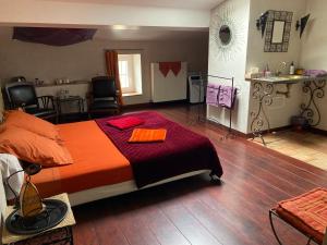 a bedroom with a large bed with an orange blanket at Aux Anges Gardiens in Carcassonne