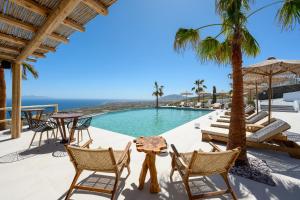 a patio with chairs and a pool with palm trees at Leon Luxury Suites in Imerovigli