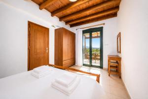 a bedroom with a white bed and a large window at Andreas Beach Villa in Sfakia +19 photos