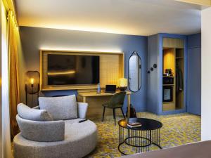 a living room with a couch and a tv at Mercure Agen Centre in Agen