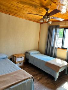 two beds in a room with a ceiling fan at Cabañas Los Robles Premium in Villa Quillinzo