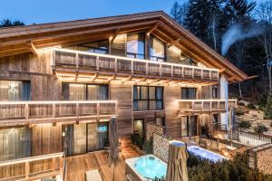 een blokhut met een terras en een hot tub bij Hotel Montchalet in Ortisei