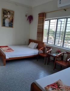 a bedroom with a bed and two chairs and windows at Thùy Dung 62 in Ha Long