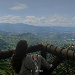 a woman sitting on the edge of a balcony looking at the mountains at Cabaña el Refugio Buenavista in Buenavista +32 photos