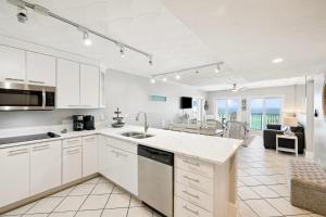 a kitchen with white cabinets and a living room at Emerald Hideaway by 30A Escapes in Carillon Beach