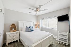 a white bedroom with a bed and a ceiling fan at Emerald Hideaway by 30A Escapes in Carillon Beach +18 photos