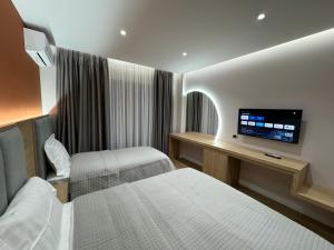 a hotel room with two beds and a flat screen tv at Kompleksi LYHNIDAS in Pogradec
