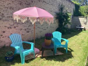 two blue chairs and a pink umbrella in a yard at Un petit truc en plus in Brienne-le-Château