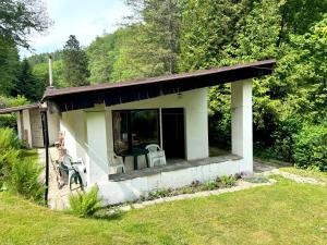 a small house with a porch and chairs in a yard at Chata Lesní Vyhlídka in Splzov