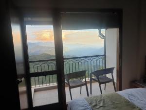 a bedroom with a bed and two chairs on a balcony at The Kumaon Retreat in Nainital +14 photos