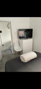 a bedroom with a bed and a tv and a chair at 2 bed- walkable train and beach apartment in Crosby
