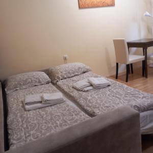 a bed with two towels on it with a table at Apartman M 5 in Novi Sad