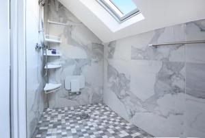 a bathroom with a shower with a marble wall at Charming loft sleeps up to 9 with spa option in Bournemouth