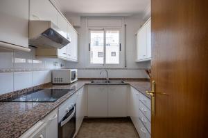 a white kitchen with a sink and a microwave at AT098 Pau Casals in Torredembarra