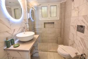 a white bathroom with a sink and a toilet at Aelia Luxury Suites Melissi in Xylokastro +60 photos