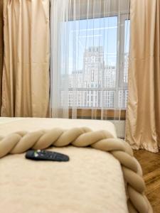 a remote control sitting on a bed in front of a window at DailyRentKZ in Kostanay