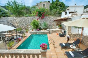 a swimming pool in a yard with a stone wall at Petit Caimari - Turismo de interior in Caimari