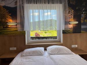 two beds in a bedroom with a window at Guesthouse Ema in Bohinj