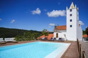 a pool in front of a building with a lighthouse at Quinta da Abelheira 1660 in Sobral da Abelheira
