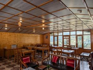 a restaurant with wooden tables and chairs and windows at pristine mountain lodge in Chail