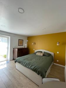 a bedroom with a bed and a yellow wall at La MaiZon in Lazenay
