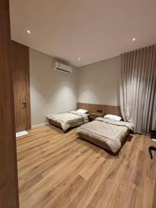 two beds in a room with a wooden floor at شاليه بالم ون و فيلورا الفندقي in Buraydah +18 photos
