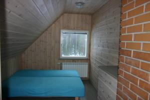 a small room with a blue bed and a window at Põhjakalda in Nüpli