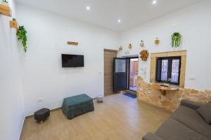 a living room with a couch and a tv on a wall at Il Cortile della Patrona in Syracuse