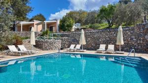 a swimming pool with chairs and umbrellas in front of a house at D&C Göcek Hotel in Göcek