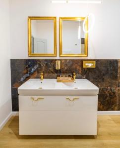 a bathroom with a white sink and two mirrors at Grand Danube Hotel in Komárno