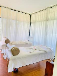 three beds in a room with white curtains at Lake Elementaita Manor in Gilgil