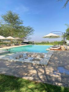 a swimming pool with chairs and an umbrella at Lake Elementaita Manor in Gilgil