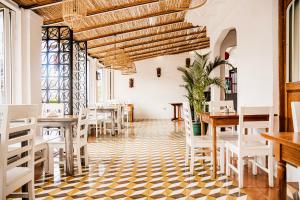 a restaurant with white tables and chairs and a checkered floor at Hotel Luz de Luna Barrio Escalante in San José