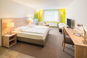 a hotel room with a bed and a desk at Hotel Westerfeld in Hemmingen +63 photos