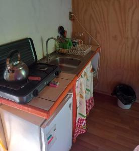 a kitchen counter with a sink and a tea kettle at Cabañita en la Isla in Isla Negra