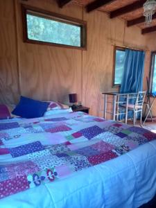 a bedroom with a bed with a quilt on it at Cabañita en la Isla in Isla Negra